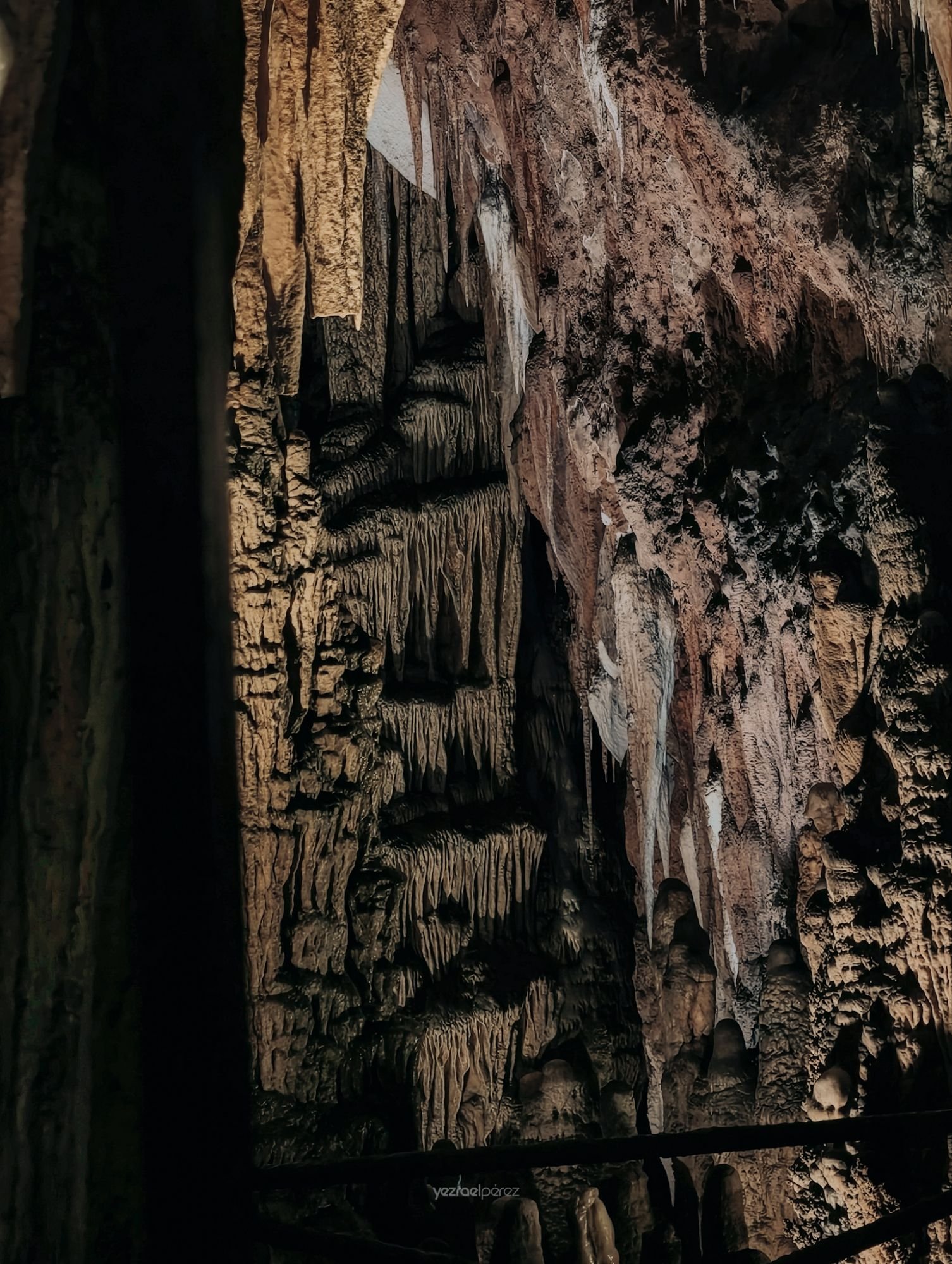 Interior de caverna con formaciones de estalactitas y estalagmitas de piedra caliza iluminadas por luz natural