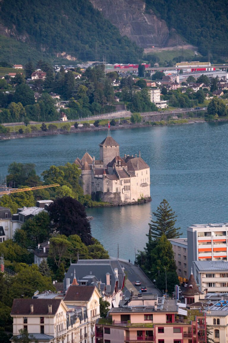 Castillo de Chillon en el lago Lemán, Suiza, rodeado de agua con viñedos y montañas boscosas al fondo